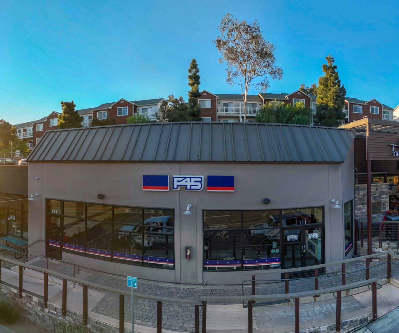 The glass-fronted corner fitness studio at dusk, with the hillside behind